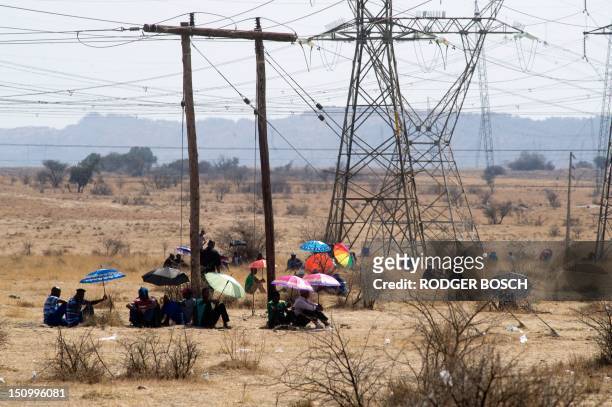 Striking Lonmin mine workers wait in the sun for a report about the state of their wage negotiations, in Marikana, North-West Province, on August 30,...