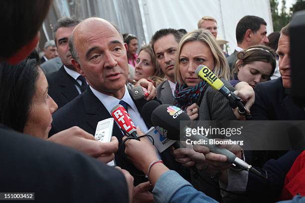 Pierre Moscovici, France's finance minister, is surrounded by reporters after speaking at a plenary session during the Mouvement des Enterprises de...