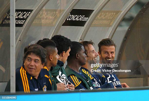 David Beckham and teammate Mike Magee of the Los Angeles Galaxy share a laugh in the bench area during their group stage CONCACAF Champions League...