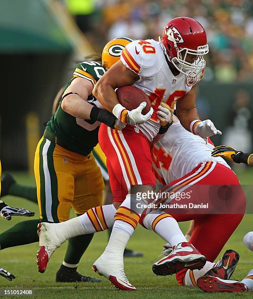 Peyton Hillis of the Kansas City Chiefs is grabbed from behind by A.J. Hawk of the Green Bay Packers during a preseason game at Lambeau Field on...