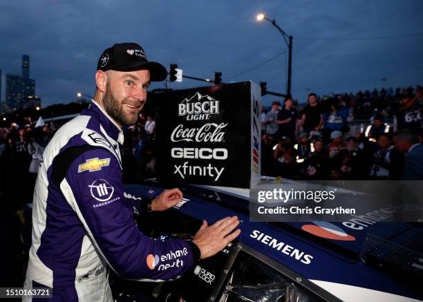 Shane Van Gisbergen, driver of the Enhance Health Chevrolet, places the winner sticker on his car in victory lane after winning the NASCAR Cup Series...