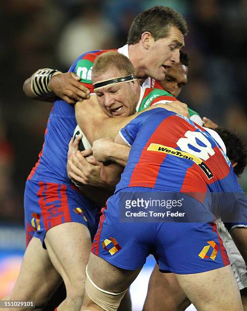 Michael Crocker of the Rabbitohs is tackled by the Knights defence during the round 26 NRL match between the Newcastle Knights and the South Sydney...