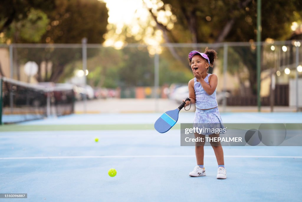 Five years old happy girl goofing around during a pickle ball practice