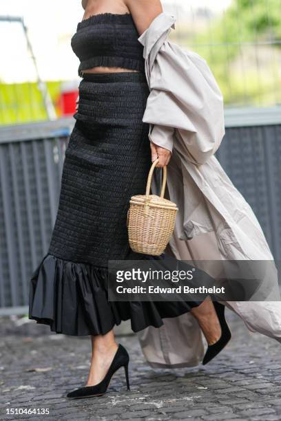Clotilde Courau wears a black ruffled shoulder-off / cropped top, a black ruffled high waist tube skirt with ruffled silk borders, a white latte...