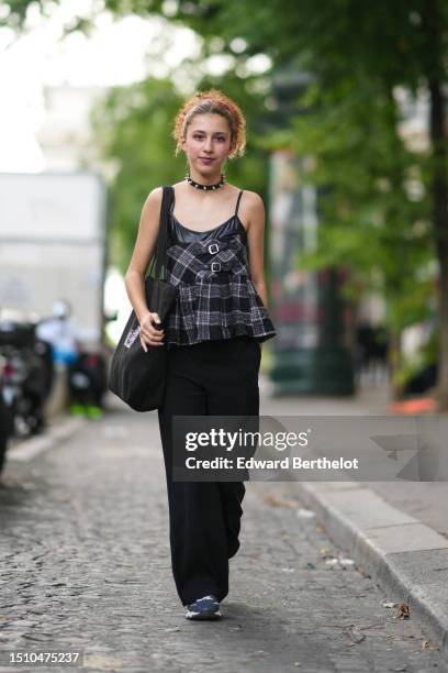 Caroline Takrarit wears a black shiny leather with silver large studded / nailed necklace, a black and white checkered print pattern belted /...