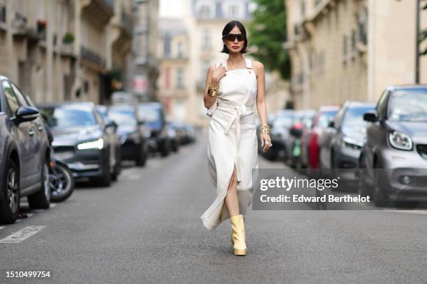 Heart Evangelista wears black futurist sunglasses from Bollé x Patou, a white latte tank-top buttoned / belted cut-out waist top from Patou, a...