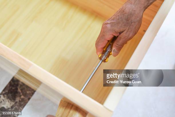installing furniture, the carpenter is fixing screws on the cabinet. - handyman stockfoto's en -beelden