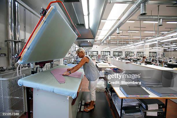 An employee prepares a garment on the bed of an industrial press during the manufacturing stages inside Brunello Cucinelli SpA's production facility...