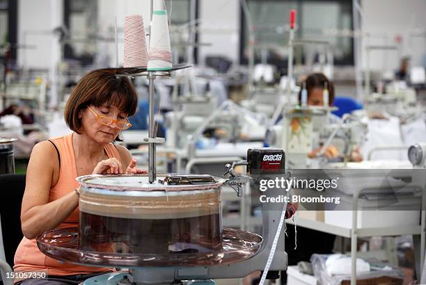 An employee feeds cashmere threads into a sewing machine during the manufacturing stages of garment production at Brunello Cucinelli SpA's facility...