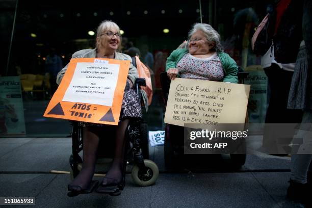 Protesters in wheelchairs carry placards during a protest against multinational IT firm and Paralympics sponsor Atos outside the company's head...