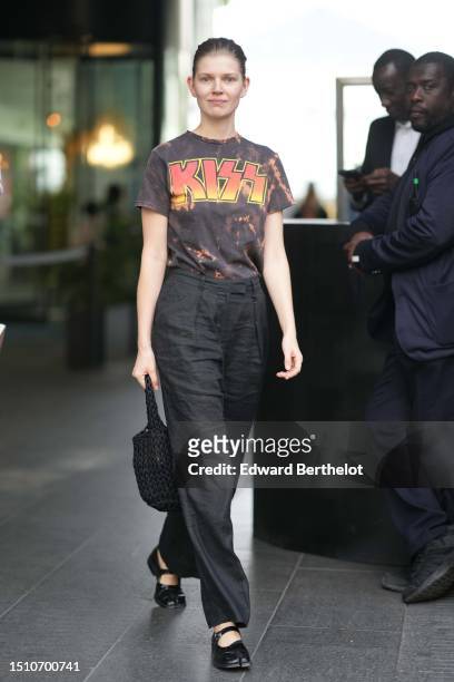 Guest wears a black and orange tie and dye print pattern with orange and yellow Kiss inscription pattern t-shirt, black puffy suit pants, a black...
