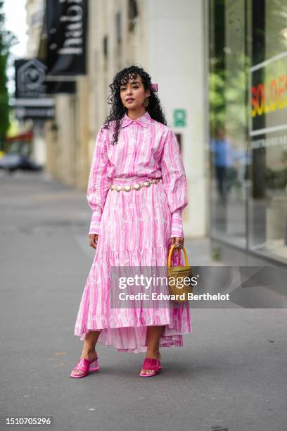 Guest wears a pink knot hair clip, a white and pink striped print pattern shirt neck / long sleeves / long flowing dress, a yellow braided wickers...