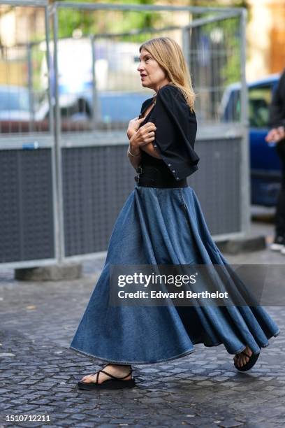 Guest wears a black t-shirt, a black cardigan, a navy blue denim pleated long skirt, black strappy flip flop sandals , outside Patou, on July 02,...