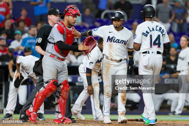 Luis Arraez of the Miami Marlins gets in between teammate Bryan De La Cruz and catcher Willson Contreras of the St. Louis Cardinals during an...