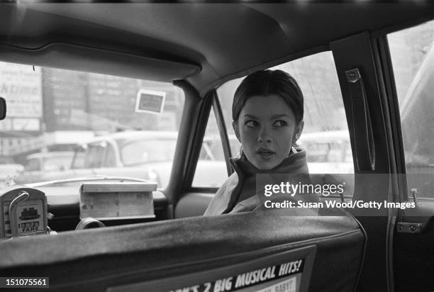 Canadian film and stage actress Genevieve Bujold rides in the front seat of a cab, New York, New York, August 1968.