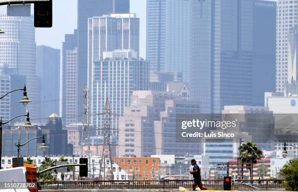 Los Angeles, CA - A jogger is dwarfed by the downtown Los Angeles skyline on a warm Thuisday afternoon, July 6, 2023. A heatwave is forecast for Los...
