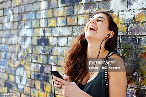young woman laughing with smart phone + headphones - music graffiti stock pictures, royalty-free photos & images