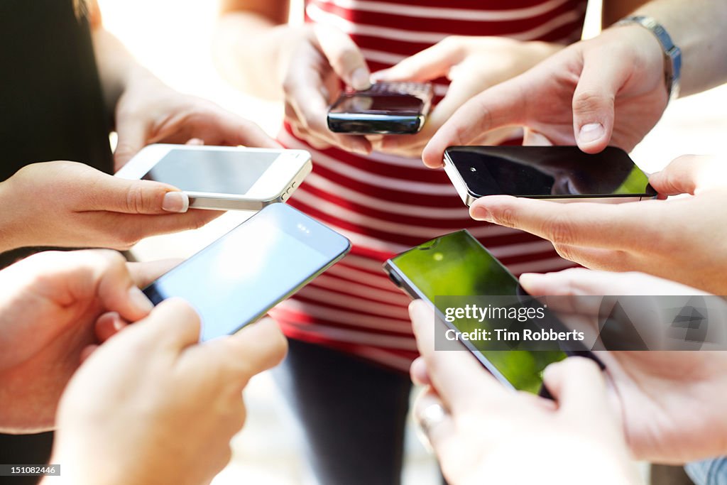 Close up of friends with circle of smart phones