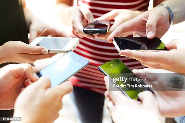 close up of friends with circle of smart phones - phone comparison stock pictures, royalty-free photos & images