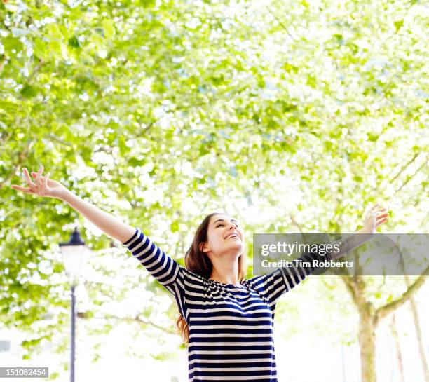 young woman next to trees with arms in the air - carefree happy stock pictures, royalty-free photos & images