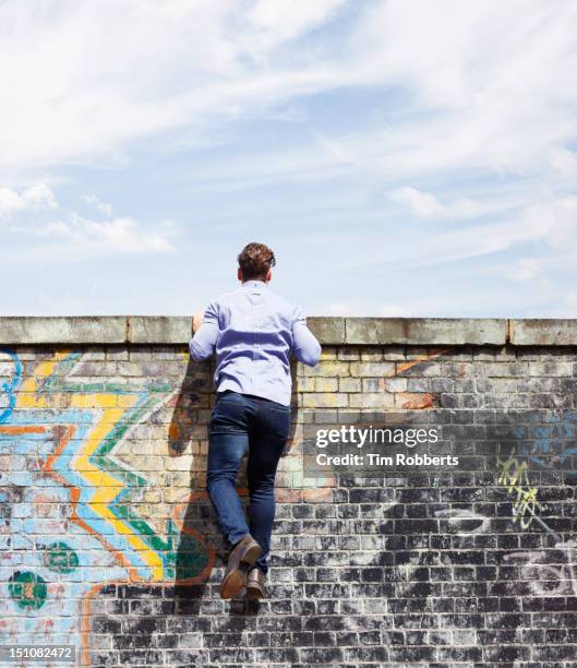 man peering over wall. - graffiti wand stock-fotos und bilder