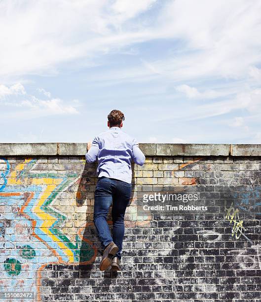 man peering over wall. - curiosity stock pictures, royalty-free photos & images
