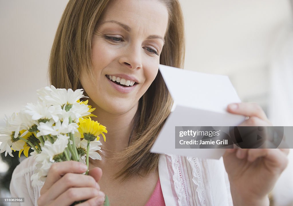 Woman with bouquet of flowers reading card