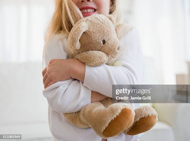 young girl hugging teddy bear - teddybär stock-fotos und bilder