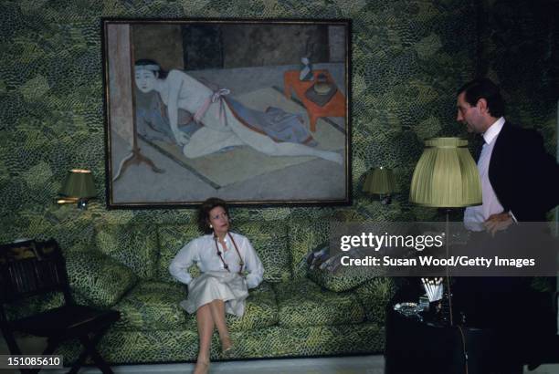 French-born businesswoman Helene Rochas , President of Marcel Rochas perfume and fashion house, listens to an unidentified man as she sits on a sofa...