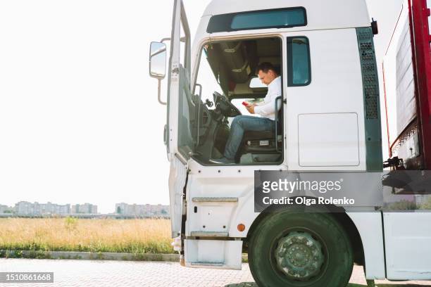 truck driver in the cab of the white truck using smartphone - calling a cab stock-fotos und bilder