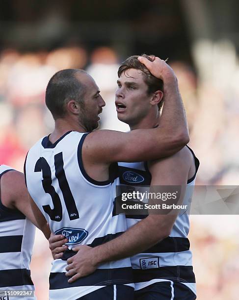 Tom Hawkins of the Cats is embraced by James Podsiadly after kicking a goal during the round 23 AFL match between the Geelong Cats and the Sydney...