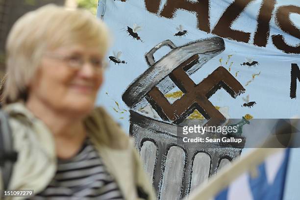 An activist stands in front of a banner showing a swastika being dumped into a garbage can during a demonstration to celebrate a court order banning...