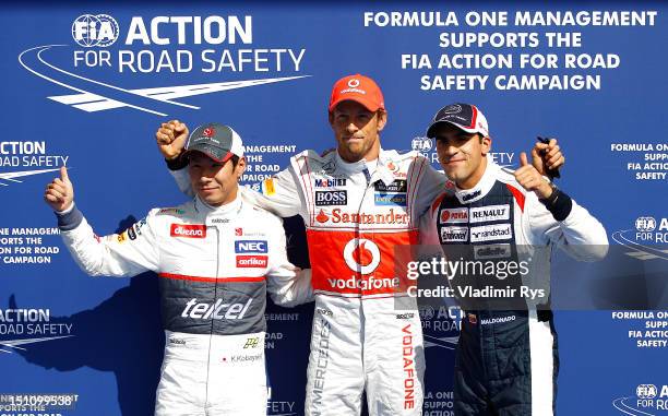 Pole sitter Jenson Button of Great Britain and McLaren poses for a photo together with Kamui Kobayashi of Japan and Sauber finishing second and...