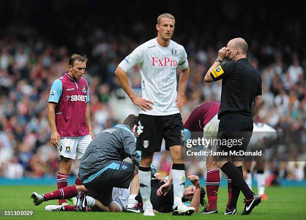 Andy Carroll of West Ham United clashes with Brede Hangeland of Fulham and is forced to leave the pitch during the Barclays Premier League match...