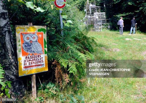 Placard reading "Shadows and Lights' Smugglers" is pictured on August 29, 2012 in Moussey, northeastern France, while people are looking at an...