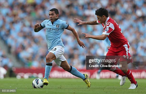 Carlos Tevez of Manchester City moves away from Alejandro Faurlin of Queens Park Rangers during the Barclays Premier League match between Manchester...