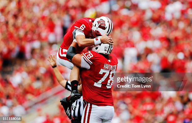 Quarterback Danny O'Brien of the Wisconsin Badgers leaps into the arms of teammate tackle Rob Havenstein after the Badgers score their first...