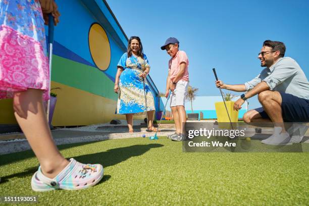 family playing miniature golf while on holiday. - mini golf stock pictures, royalty-free photos & images