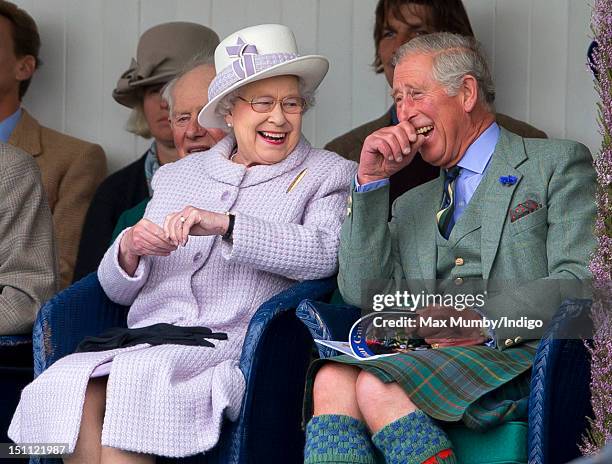 Queen Elizabeth II and Prince Charles, Prince of Wales laugh whilst watching the children's sack race as they attend the 2012 Braemar Highland...