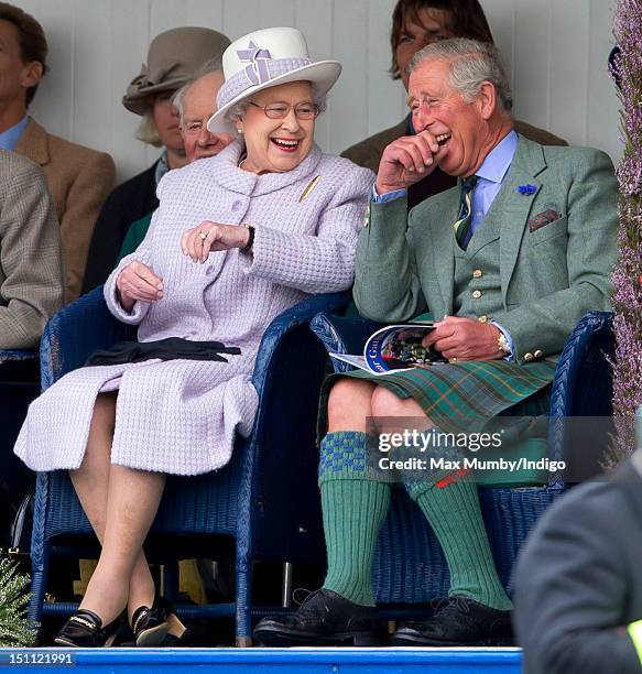 Queen Elizabeth II and Prince Charles, Prince of Wales laugh whilst watching the children's sack race as they attend the 2012 Braemar Highland...