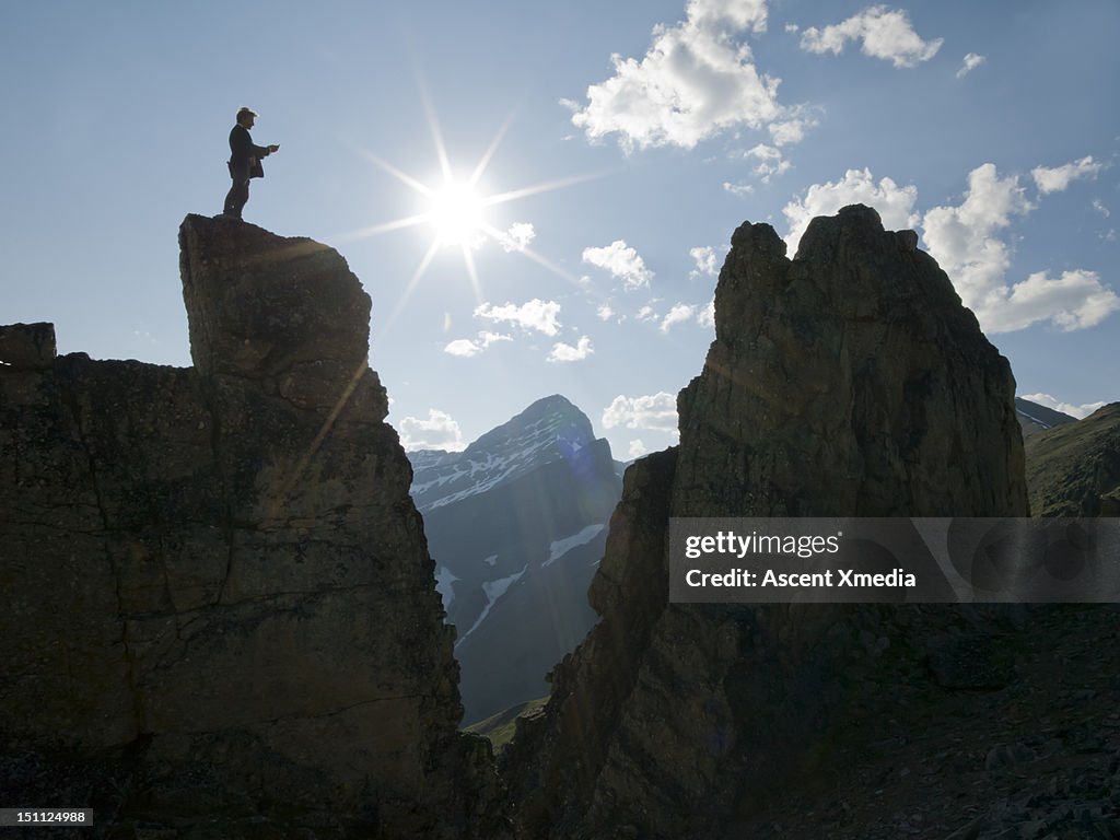 Man stands on peak, sends text.