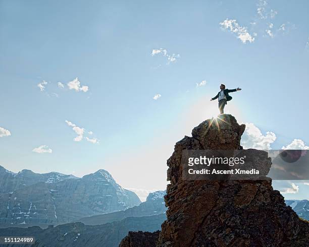 man stands on peak, arms outstretched. - success stock pictures, royalty-free photos & images