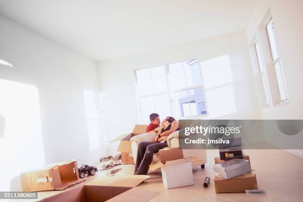 mother and son bonding in an empty room with cardboard boxes while moving in - apartment no furniture stockfoto's en -beelden