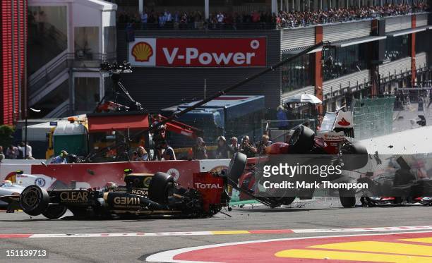 Romain Grosjean of France and Lotus and Fernando Alonso of Spain and Ferrari collide and crash out at the first corner at the start of the Belgian...