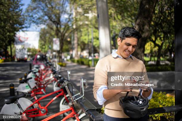 young man renting city bike - bicycle rack stock pictures, royalty-free photos & images