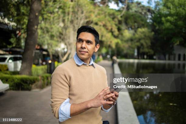 portrait of young latin man using mobile phone - smart casual men stock pictures, royalty-free photos & images