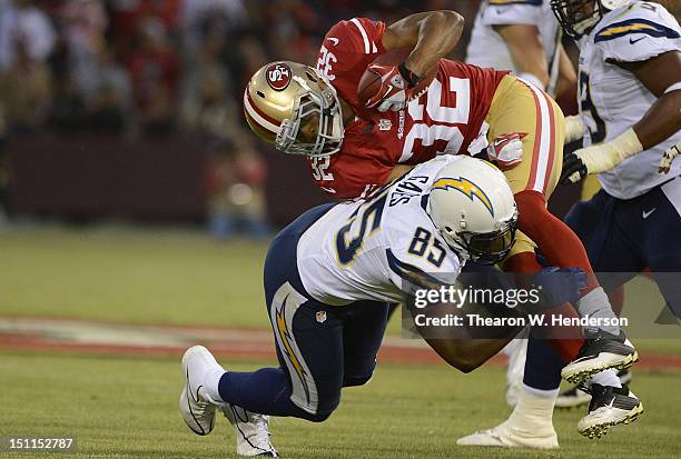 Darcel McBath of the San Francisco 49ers after intercepting a pass gets tackled by Antonio Gates of the San Diego Chargers in the first quarter of an...