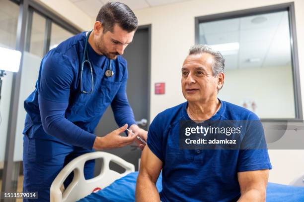 a nurse administers a vaccine to a senior man - administers stock pictures, royalty-free photos & images