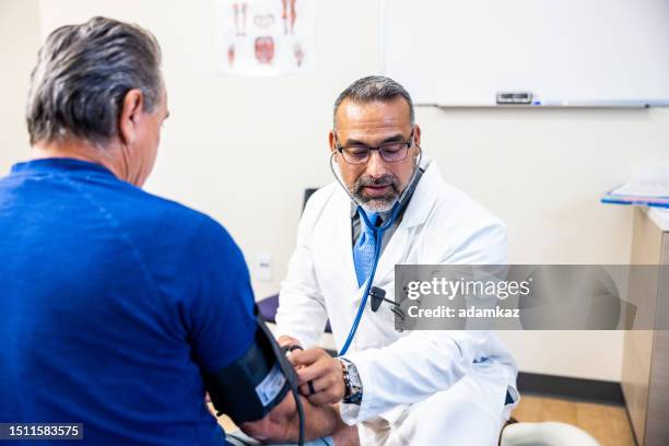 doctor taking a senior man's blood pressure reading - ateroskleros bildbanksfoton och bilder