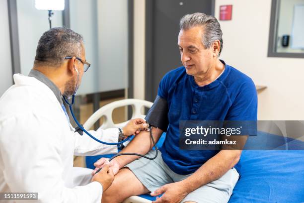 arzt, der den blutdruck eines älteren mannes misst - atherosklerose stock-fotos und bilder